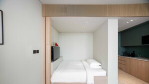 A modern bedroom with a bed, a television, and a kitchenette area. - Contemporary Studio w/ Burj View (Dubai)