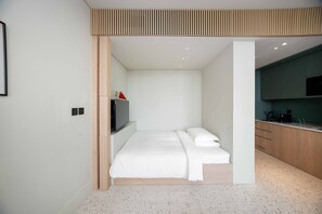 Ein modernes Schlafzimmer mit einem Bett, einem Fernseher und einer Küchenzeile.