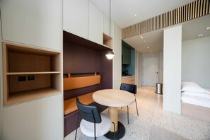 Ein modernes Hotelzimmer mit rundem Tisch, zwei Stühlen, einer Bank und einem Bett.