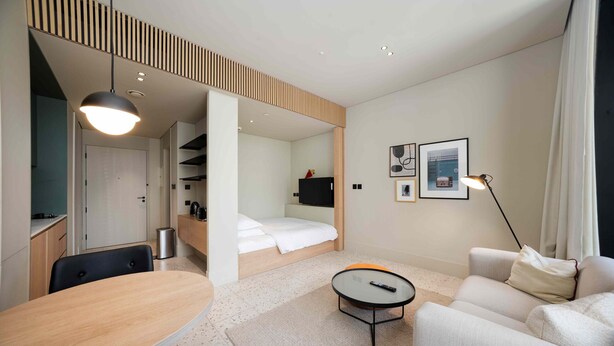 A modern hotel room with a bed, a desk, a sofa, and a coffee table. - Modern Upside Studio w/ Skyline View (Dubai)