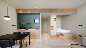 A modern hotel room with a kitchenette, a dining area, and a bed. - Prime Upside Studio w/ Private Balcony (Dubai)