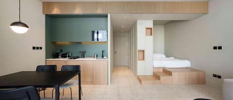 Ein modernes Hotelzimmer mit Küchenzeile, Essbereich und Bett.