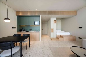 Ein modernes Hotelzimmer mit Küchenzeile, Essbereich und Bett.