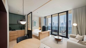 Een moderne hotelkamer met een eethoek, een bed, een televisie en uitzicht op de stad.