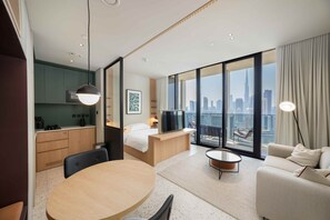 Ein modernes Hotelzimmer mit Essbereich, einem Bett, einem Fernseher und Blick auf die Stadt.