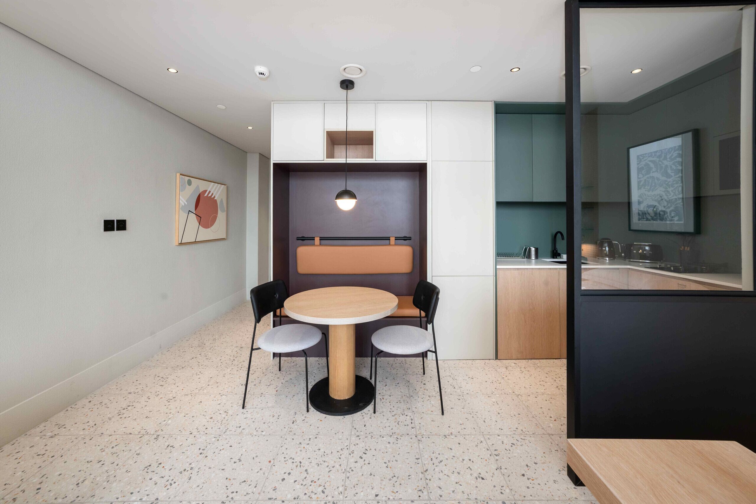 A modern dining area with a round table, four chairs, and a pendant light.