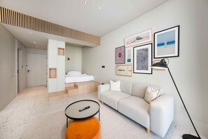 Ein modernes Wohnzimmer mit Sofa, Couchtisch und Lampe. Eine Treppe führt zu einer oberen Ebene.