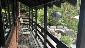 Un espace extérieur abrité, aménagé avec du mobilier en bois et offrant une vue sur un jardin.