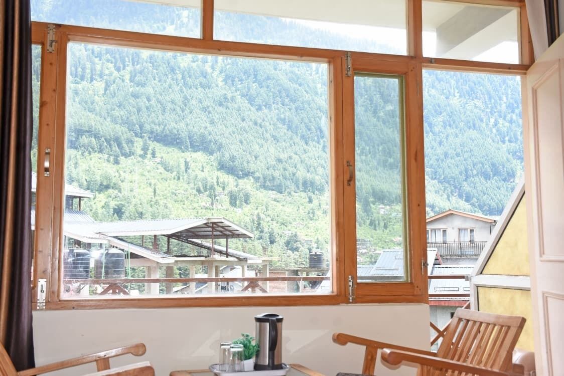 Una habitación con un ventanal grande que da a una zona montañosa boscosa.