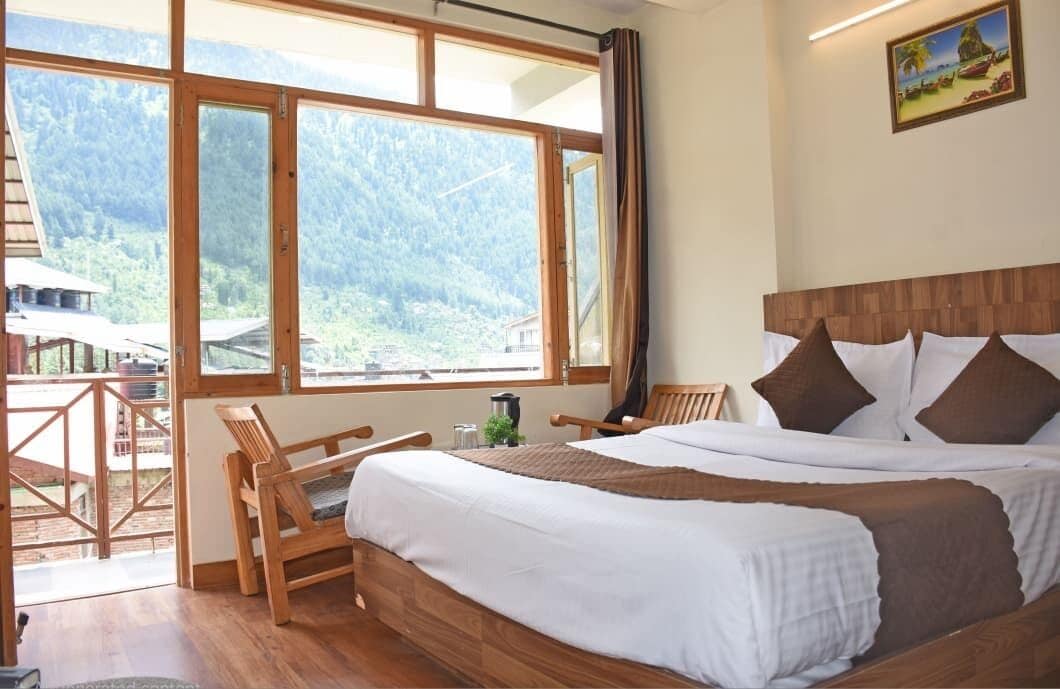 A bedroom with a large window, a wooden bed, and a view of a mountainous landscape.