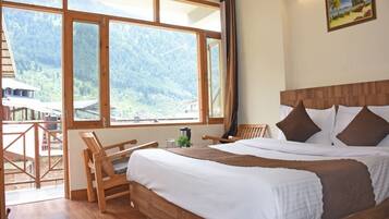 A bedroom with a large window, a wooden bed, and a view of a mountainous landscape.