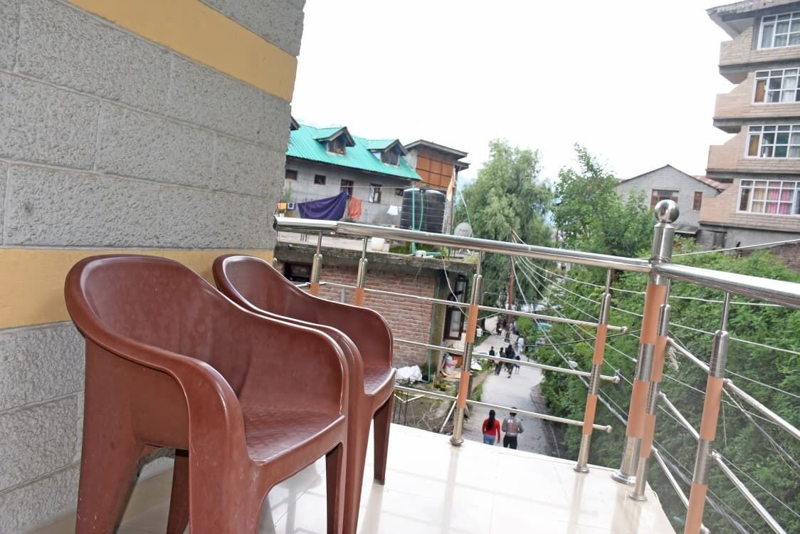A balcony with metal railings and a view of buildings and trees.