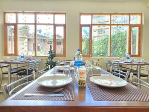 A dining area with tables set for two, equipped with plates, cutlery, and glasses. - Hotel The Destination Manali (850m from Mall Road) (Manali)