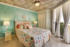 A bedroom with a bed, two bedside lamps, a ceiling fan, a window with curtains, and a wall with a decorative ceiling. - Pool, Pickleball & Beach! Gulf Island Club Condo (Hudson)