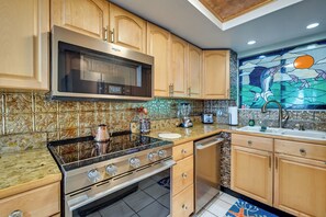 A kitchen with wooden cabinets, a stainless steel microwave, an oven, a sink, and a decorative backsplash. - Pool, Pickleball & Beach! Gulf Island Club Condo (Hudson)