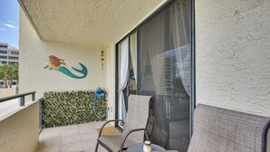 En balkon med en stol, en pyntelig vægdekoration og et vindue med gardin.