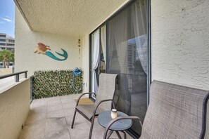 Ein Balkon mit einem Stuhl, einer Wanddekoration und einem Fenster mit Vorhang.