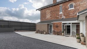 A brick building with a covered patio area, outdoor seating, and potted plants. - Annie May B&B (Devonport)