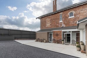 A brick building with a covered patio area, outdoor seating, and potted plants. - Annie May B&B (Devonport)