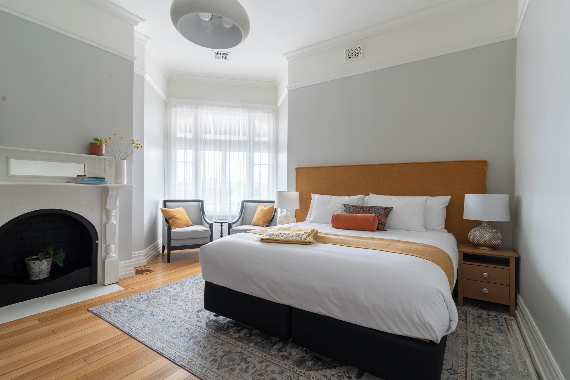 Un dormitorio con una cama, dos sillones, una chimenea y una mesita de noche.