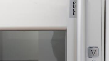 En hvid elevator med en 'PULL' skilte og en trekantet knap, sandsynligvis til nødformål.