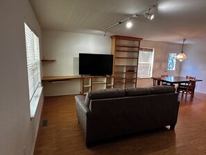 A modern living room with a flat-screen TV, a sofa, a dining table, and a chandelier. - 3-bedroom house in adorable Belgrade with cool AC (Belgrade)
