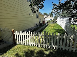 A residential property with a white picket fence, a well-maintained lawn, and a house with yellow siding. - 3-bedroom house in adorable Belgrade with cool AC (Belgrade)