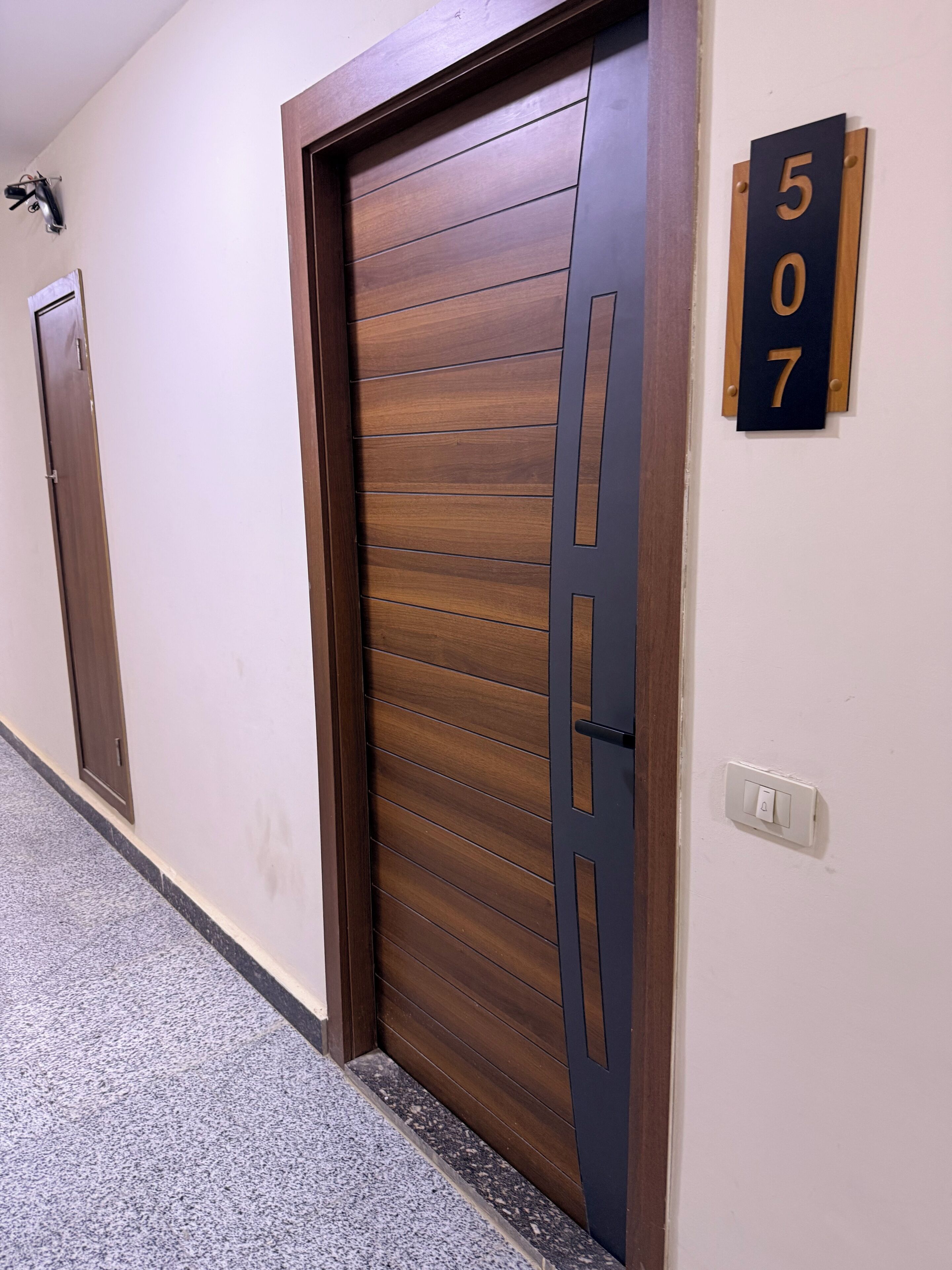 A hallway with a wooden door and a wall-mounted number plate indicating room 507.