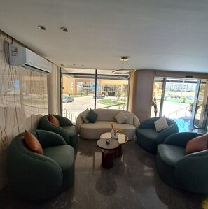 A modern lobby with seating arrangements, a coffee table, and large windows offering a view of the outside. - Serenity Sands Red Sea Hurghada (Red Sea Governorate)