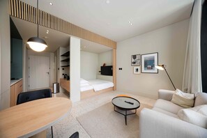 Ein modernes Hotelzimmer mit Bett, Schreibtisch, Sofa und kleinem Tisch.
