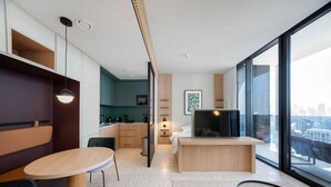 A modern hotel room with a dining area, kitchenette, and a large window offering a city view. - Bright Studio w Iconic Burj View (Dubai)