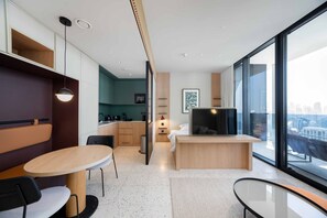 A modern hotel room with a dining area, kitchenette, and a large window offering a city view. - Bright Studio w Iconic Burj View (Dubai)