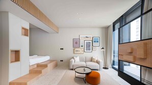 A modern living room with a sofa, coffee table, and artwork on the wall. - Upscale Business Bay Studio w Pool (Dubai)