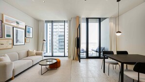 A modern living room with a sofa, coffee table, and dining area. - Upscale Business Bay Studio w Pool (Dubai)