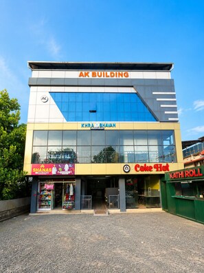 A multi-story commercial building with signage for 'AK BUILDING,' 'KHRA BHAVAN,' 'SHANAS,' 'Cake Hat,' and 'KATHI ROLL.' - Vilstay Go Malabar Comfort Rooms  (Ambalapuzha)