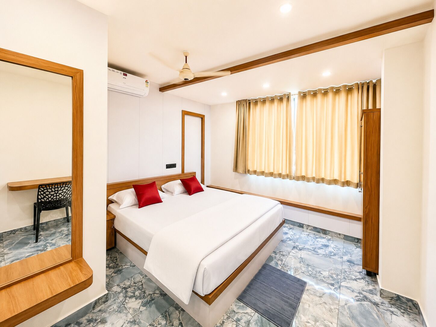 A hotel room with a bed, a window with curtains, a ceiling fan, and a mirror.