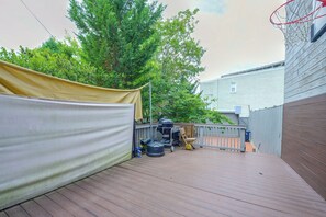 Une terrasse en bois avec un barbecue, un espace salon couvert et un panier de basketball.