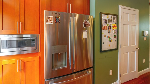 A kitchen with a stainless steel refrigerator, a microwave, wooden cabinets, and a white door. - Quiet Home in Walkable Area: 3 Mi to National Mall (Washington)