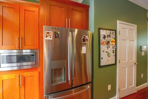 A kitchen with a stainless steel refrigerator, a microwave, wooden cabinets, and a white door. - Quiet Home in Walkable Area: 3 Mi to National Mall (Washington)