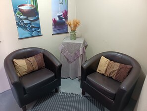 A room with two leather armchairs, a small table with a vase of dried plants, and two framed artworks on the wall. - Room-11 on High Airbnb za (Gariep)