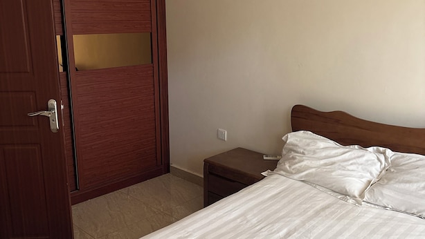 Une chambre d’hôtel comprenant un lit, une armoire en bois, une table de chevet et un appareil de climatisation.