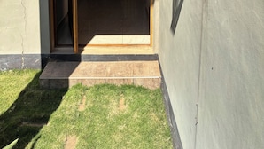Une entrée d’immeuble avec une porte en bois et une petite marche menant à un sol carrelé.
