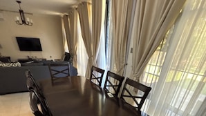 Un espace repas comprenant une grande table et des chaises, un canapé et un téléviseur.