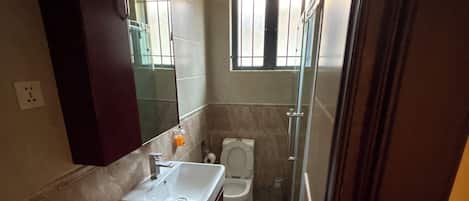A bathroom with a sink, toilet, and shower area.