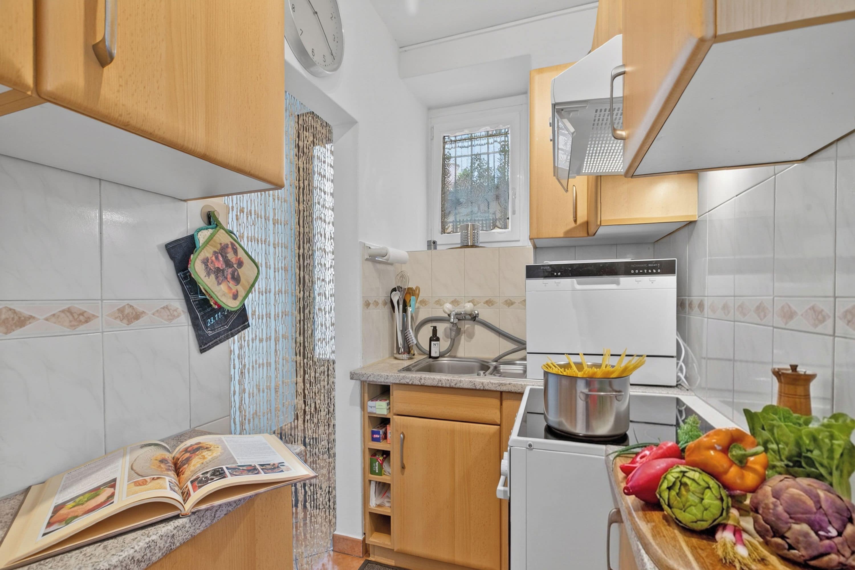 A kitchen with a sink, stove, and various food items on the counter.