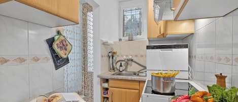 A kitchen with a sink, stove, and various food items on the counter.