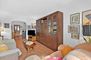 A living room with a sofa, a television, a cabinet, and framed pictures on the wall. - Casa Berta Brissago 1 With Balcony for Four (Brissago)