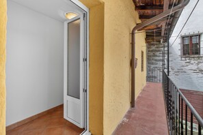 Ein Balkon mit Steinmauer, einer Tür und einem Fenster mit Rollläden.