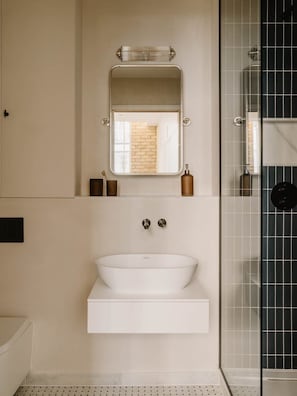 A modern bathroom with a large mirror, a white sink, and a glass shower enclosure. - Fulham Residences Two (London)