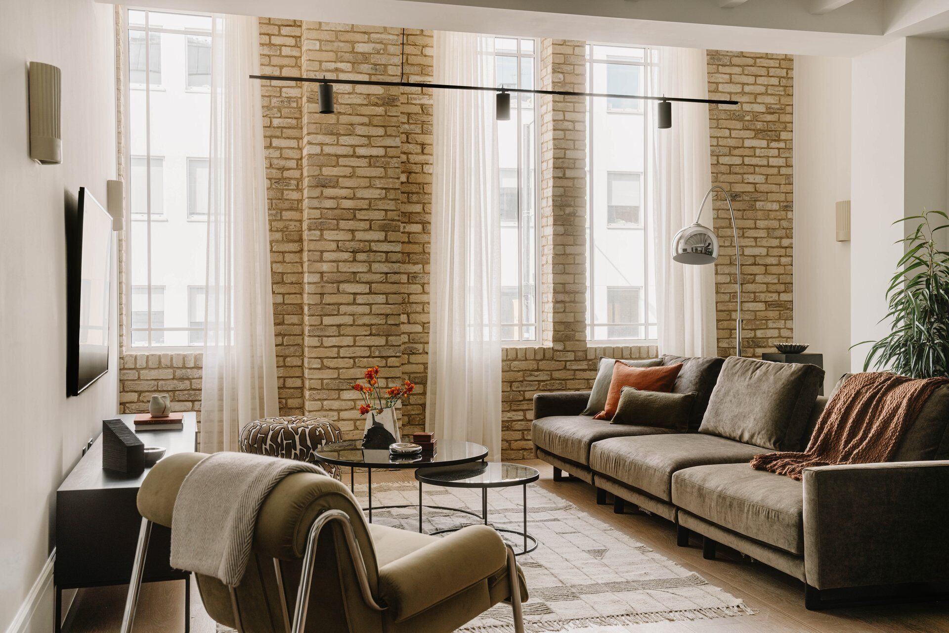 A living room with a brick wall, a sofa, a coffee table, a chair, and a TV.